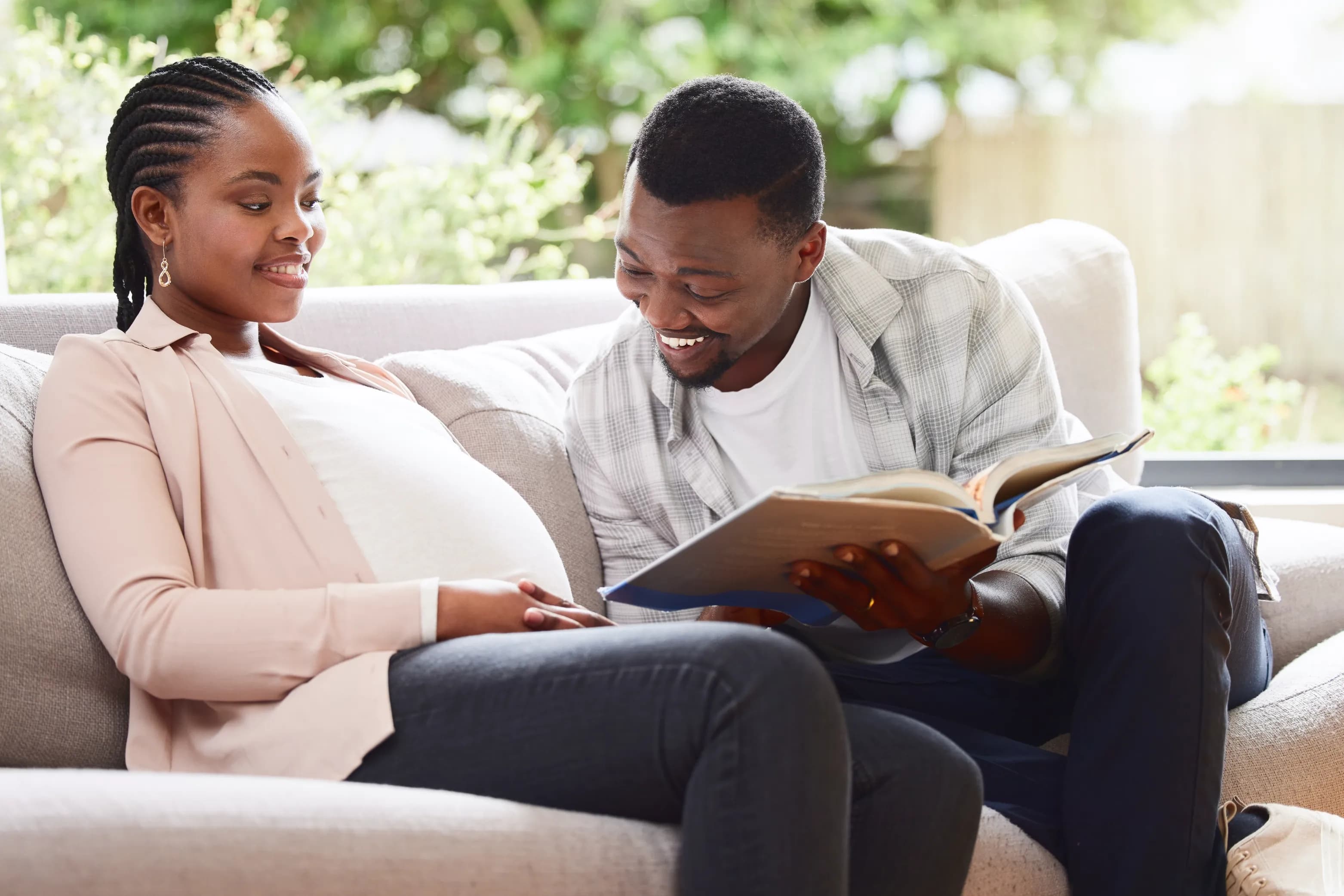 Expecting parents reviewing a book together while planning postpartum support at home.